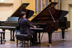 Adult man playing grand piano on stage
